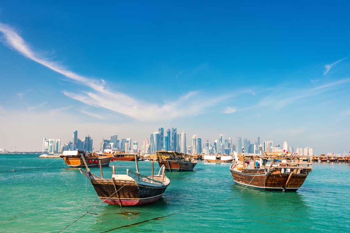 Uferpromenade in Doha, Katar, mit traditionellen kleinen Holzschiffen, den so genannten Dhows, und der Skyline der Stadt