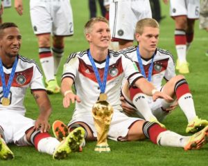 Der deutsche Mittelfeldspieler Bastian Schweinsteiger (C) sitzt mit dem WM-Pokal in der Hand, während seine Mannschaft den 1:0-Sieg im Finale der FIFA Fußball-Weltmeisterschaft 2014 zwischen Deutschland und Argentinien nach der Verlängerung im Maracana-Stadion in Rio de Janeiro, Brasilien, feiert. AFP PHOTO / PATRIK STOLLARZ