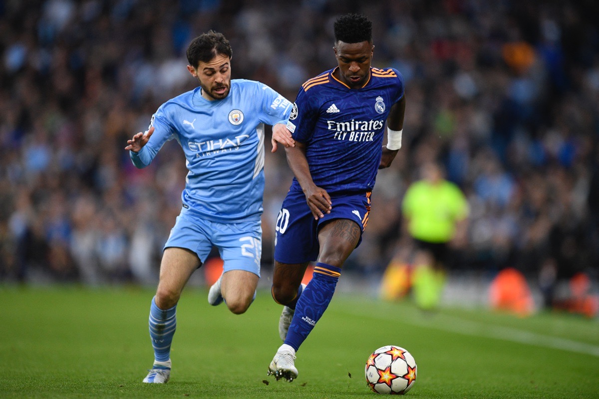 Manchester Citys portugiesischer Mittelfeldspieler Bernardo Silva (L) kämpft mit Real Madrids brasilianischem Stürmer Vinicius Junior um den Ball während des Halbfinal-Hinspiels der UEFA Champions League zwischen Manchester City und Real Madrid im Etihad-Stadion in Manchester am 26. April 2022. (Foto: Oli SCARFF / AFP)