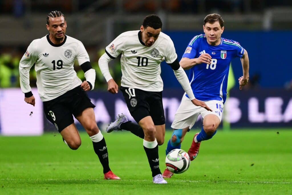 Der deutsche Stürmer (19) Leroy Sane und der deutsche Mittelfeldspieler (10) Jamal Musiala kämpfen mit dem italienischen Mittelfeldspieler (18) Nicolo Barella während des Viertelfinal-Hinspiels der Fußball-Nationalmannschaft zwischen Italien und Deutschland am 20. März 2025 im San-Siro-Stadion in Mailand um den Ball. (Foto: Marco BERTORELLO / AFP)